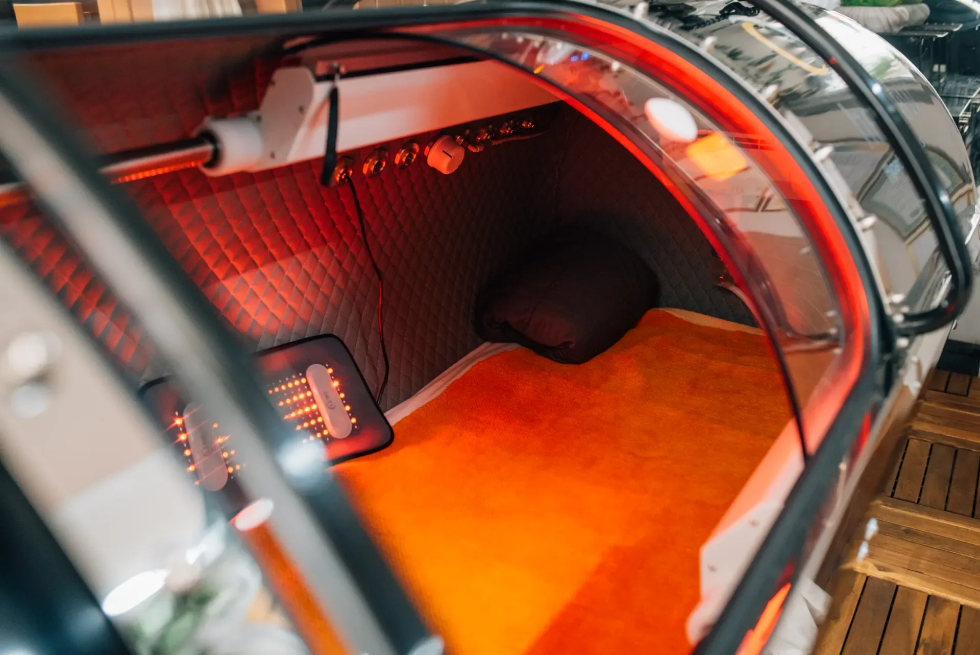 Hyperbaric chamber interior with red light panels and a resting area